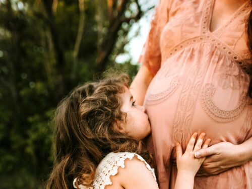 dziewczynka całująca brzuch kobiety w ciąży, autorka Jessica Rockowitz